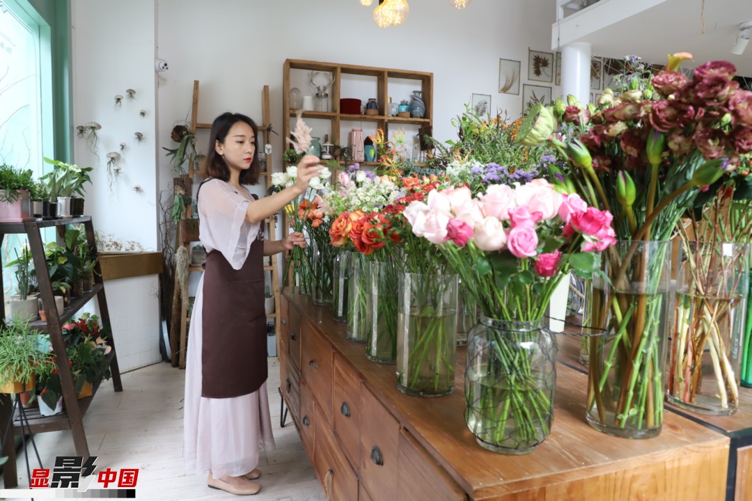 王黎媛是一名河南姑娘，在昆明念完大學(xué)后，就再也舍不下春城的藍(lán)天陽光、青山碧水，更舍不下這里的四時(shí)繁花，于是就干脆留了下來，成了一名媒體人。2017年的時(shí)候又毅然辭去工作，創(chuàng)業(yè)開起了花店，成了都市里的一名“花房姑娘”。圖為王黎媛在自己的花店中整理鮮花。新華網(wǎng) 周亞平/攝 念新洪/文